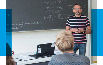 Ein Professor erklärt mathematische Formeln an einer Tafel einer Gruppe von Studierenden.