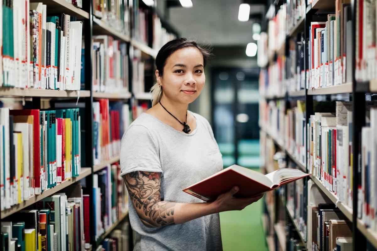 Publications Eine Frau hält in der Bibliothek ein Buch in der Hand