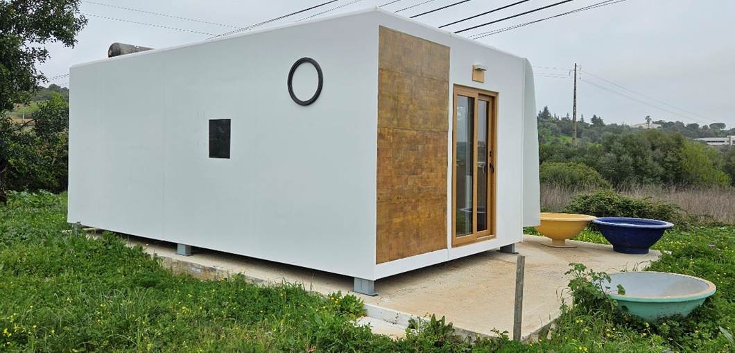 Tiny House Rocca Kompaktes Tiny House mit moderner Architektur, steht auf einer Wiese Rotorblättern